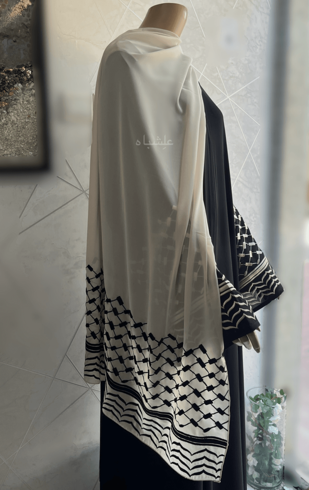 Abaya crafted from premium Nida fabric featuring intricate Keffiyeh embroidery on the sleeves and a soft chiffon Sheila. The Alishbah Keffiyeh Design Abaya blends contemporary elegance with cultural heritage, offering a sophisticated and graceful look.