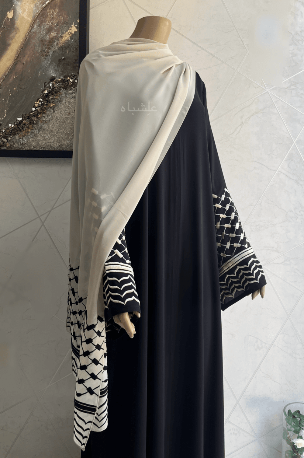 Abaya crafted from premium Nida fabric featuring intricate Keffiyeh embroidery on the sleeves and a soft chiffon Sheila. The Alishbah Keffiyeh Design Abaya blends contemporary elegance with cultural heritage, offering a sophisticated and graceful look.