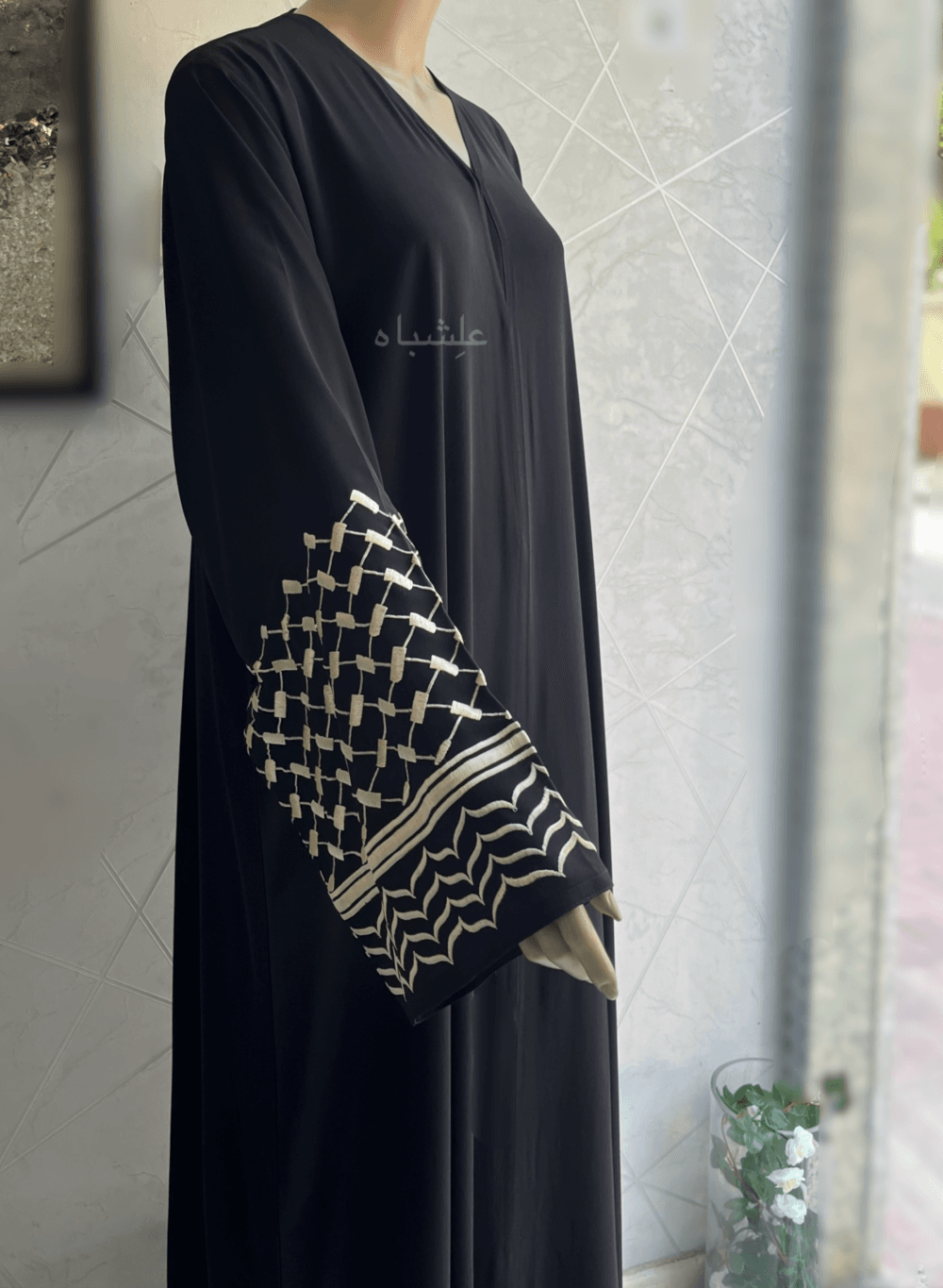 Abaya crafted from premium Nida fabric featuring intricate Keffiyeh embroidery on the sleeves and a soft chiffon Sheila. The Alishbah Keffiyeh Design Abaya blends contemporary elegance with cultural heritage, offering a sophisticated and graceful look.