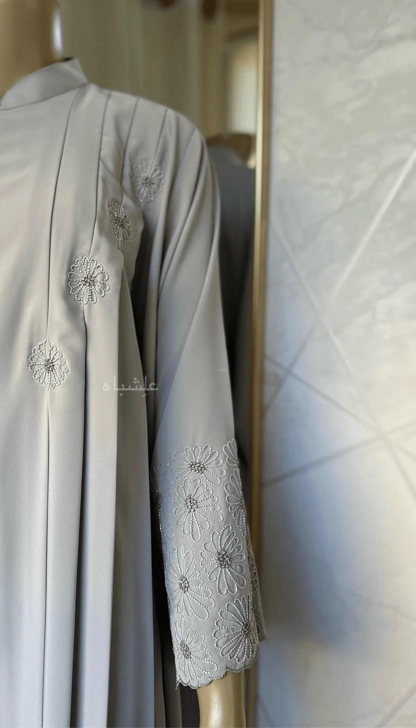 Eternal Petals of Grace Nida Premium Abaya with Floral Handwork 3 Alishbah Eternal Petals of Grace Nida Premium Abaya with floral handwork. The abaya is crafted from luxurious Nida Premium fabric, featuring delicate floral handwork including tiny scallops and French knots that form elegant patterns along the cuffs and neckline. The ensemble is completed with a soft chiffon sheila (headscarf) that drapes gracefully, enhancing the sophisticated and timeless design. This abaya blends traditional handwork with contemporary elegance, showcasing high-quality craftsmanship and refined style.