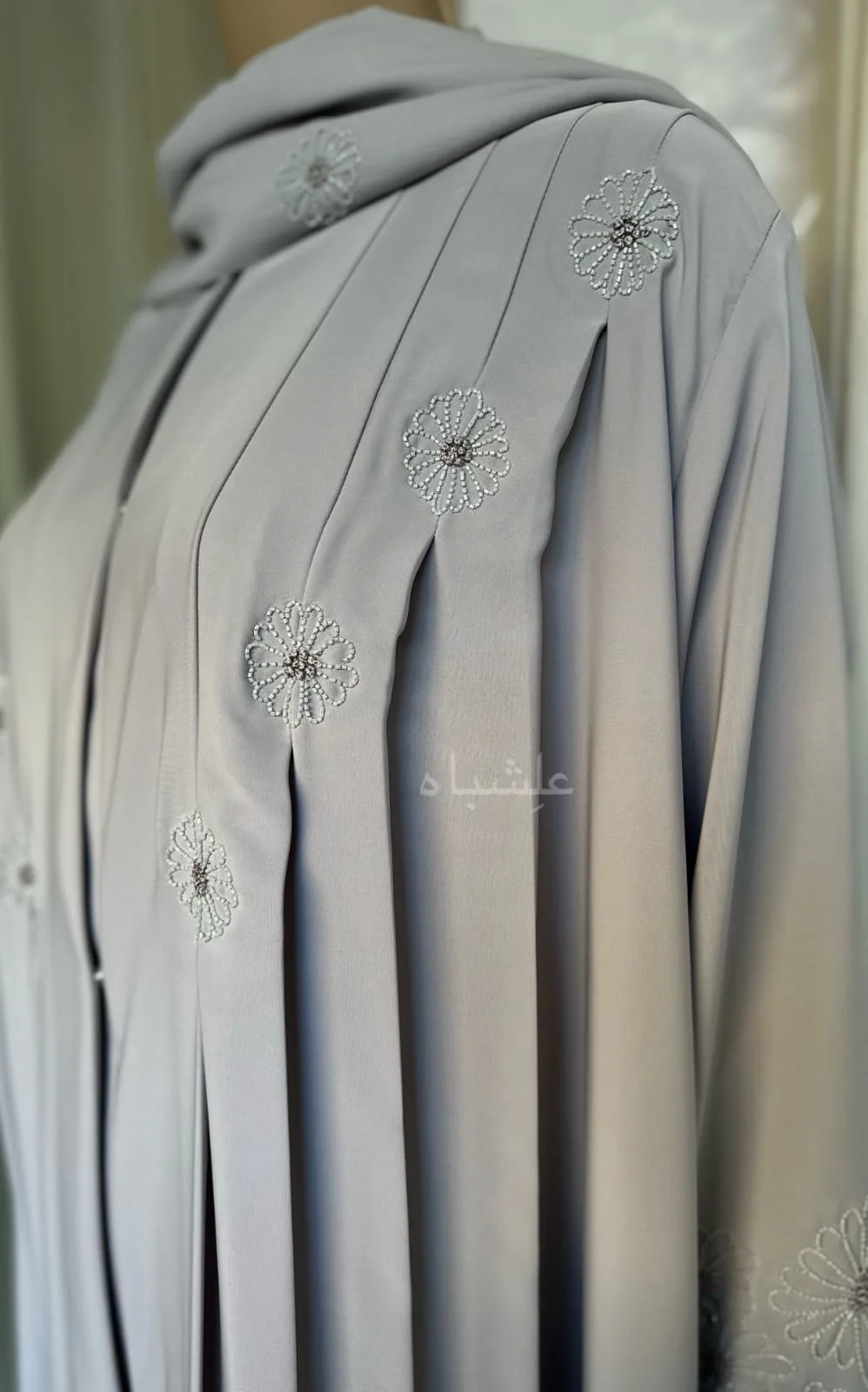 Eternal Petals of Grace Nida Premium Abaya with Floral Handwork 1 Alishbah Eternal Petals of Grace Nida Premium Abaya with floral handwork. The abaya is crafted from luxurious Nida Premium fabric, featuring delicate floral handwork including tiny scallops and French knots that form elegant patterns along the cuffs and neckline. The ensemble is completed with a soft chiffon sheila (headscarf) that drapes gracefully, enhancing the sophisticated and timeless design. This abaya blends traditional handwork with contemporary elegance, showcasing high-quality craftsmanship and refined style.