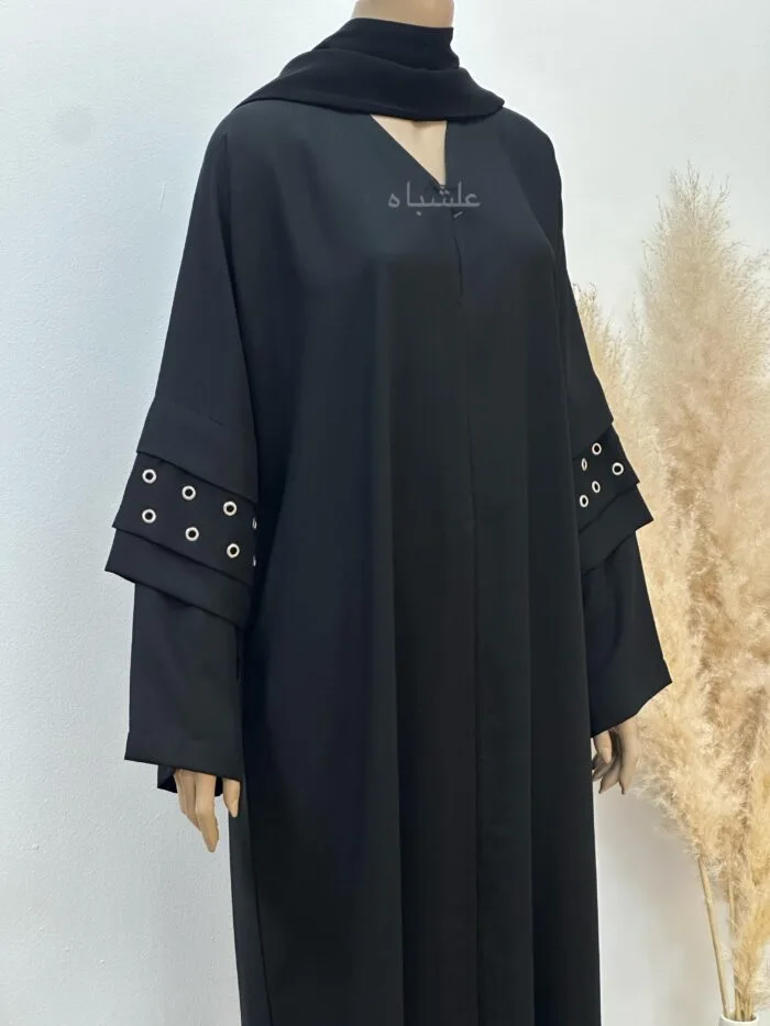 A stylish Korean crape abaya featuring handcrafted button hole embellishments, paired with a soft chiffon Sheila for versatile styling