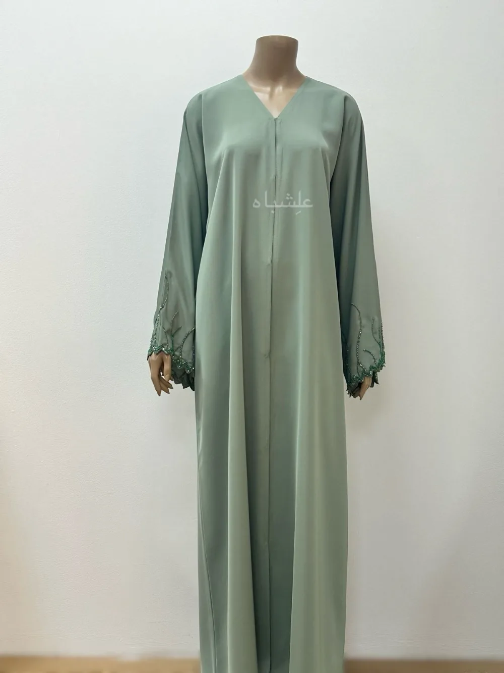 "Emerald Dawn Abaya by Alishbah featuring a vibrant emerald green color with zig-zag cut sleeves, adorned with dazzling crystals and beadwork. Accompanied by a matching sheila, the abaya combines modern design with timeless elegance, perfect for special occasions. The luxurious fabric and intricate embellishments create a sophisticated and radiant look."