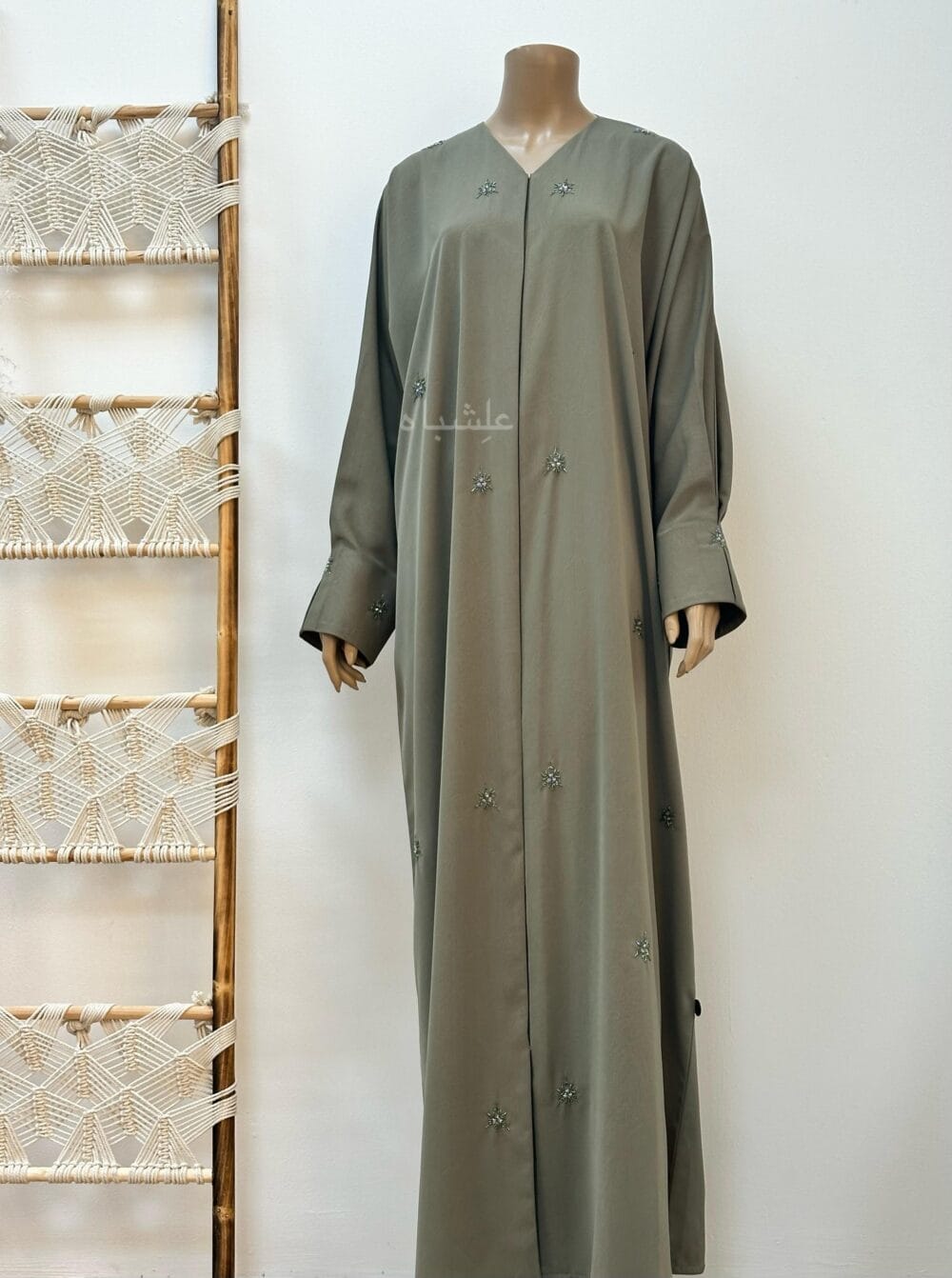 "Olive green abaya with a subtle marble crush design, adorned with snowflake-inspired crystals and delicate stone embellishments, exuding timeless elegance and enchantment."