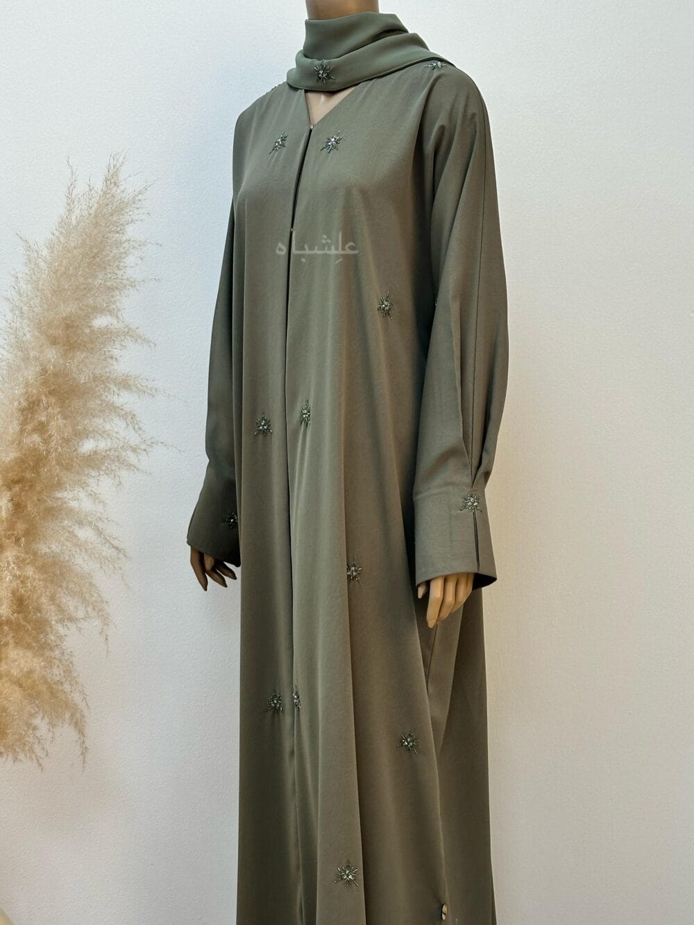 "Olive green abaya with a subtle marble crush design, adorned with snowflake-inspired crystals and delicate stone embellishments, exuding timeless elegance and enchantment."