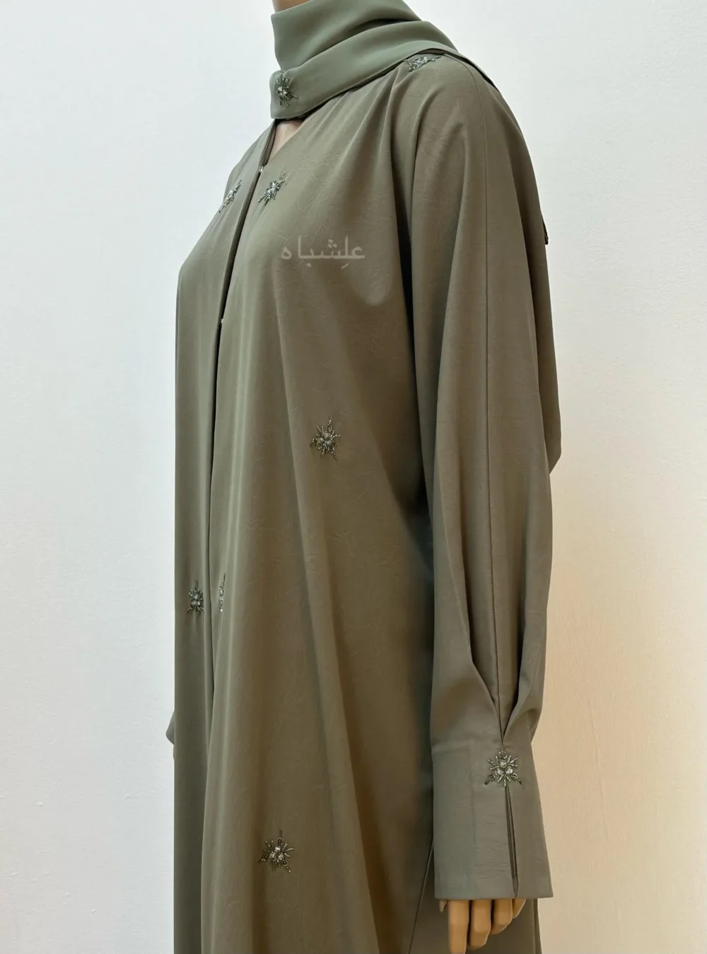 "Olive green abaya with a subtle marble crush design, adorned with snowflake-inspired crystals and delicate stone embellishments, exuding timeless elegance and enchantment."