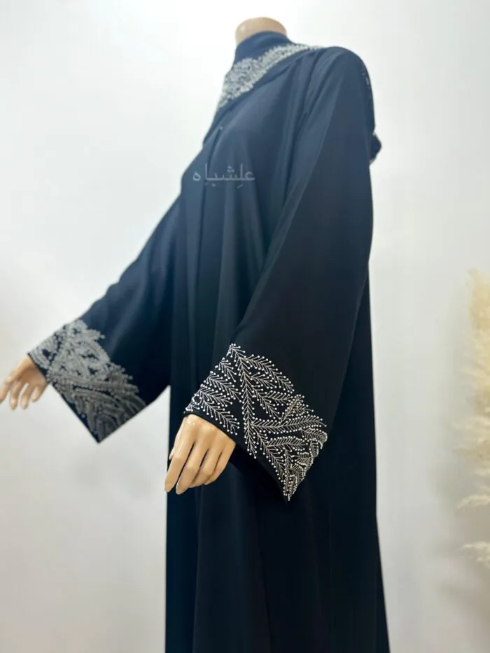 Side view of Elegant black abaya with intricate handwork and machine embroidery on the sleeves, crafted from premium Nida fabric, paired with a matching chiffon Sheila