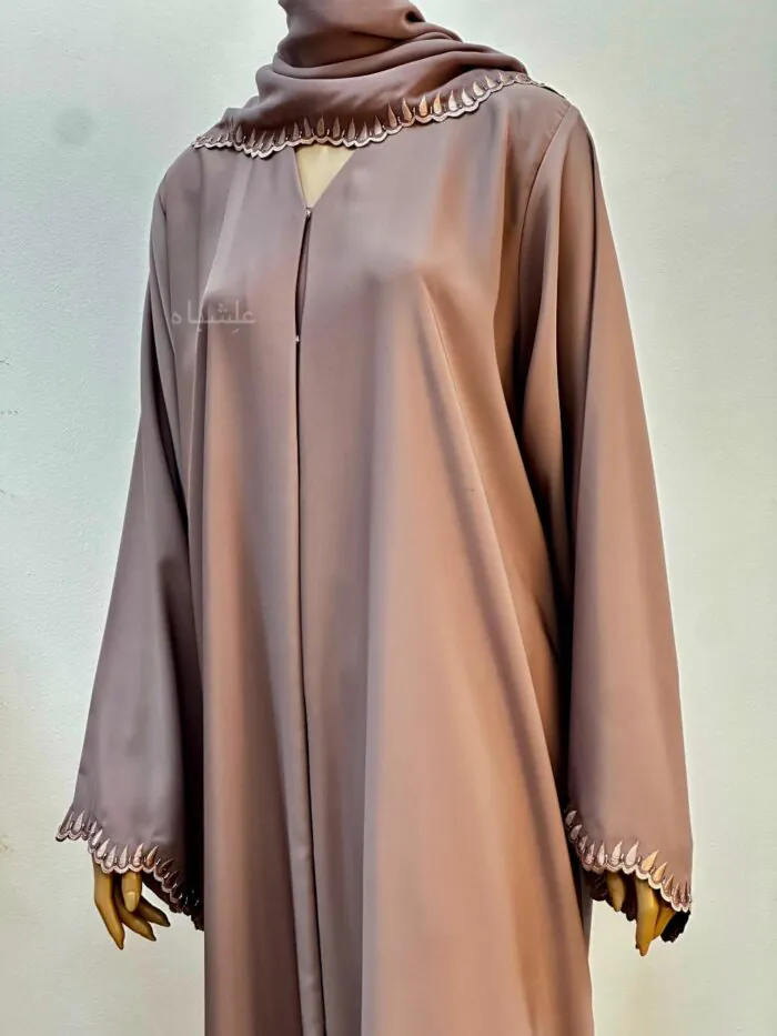 Close up shot of modest chiffon abaya in a soft, earthy tone with intricate single-line embroidery along the neckline and sleeve hems. The abaya is paired with a matching soft chiffon sheila.