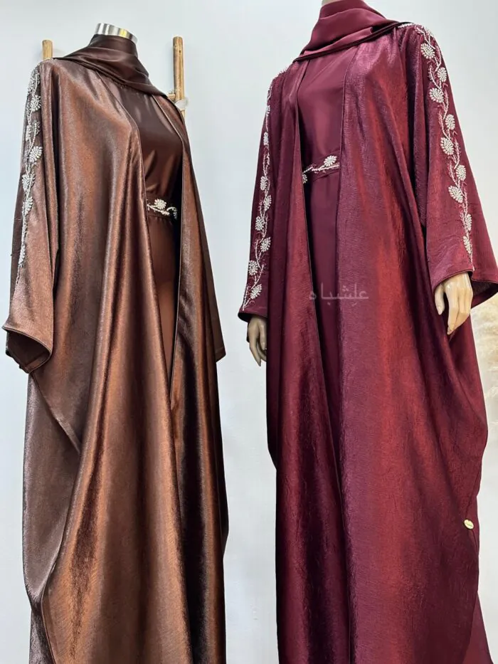 A maroon and bronze abaya with delicate handwork on the sleeves and belt, featuring an inner layer and a belt that enhances the silhouette with a graceful flow.