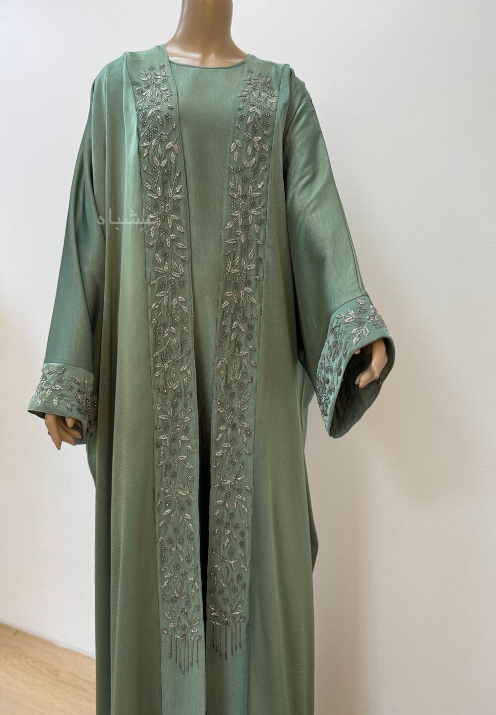 Full view of Sage green abaya with intricate floral and leaf handwork along the front and cuffs, crafted from Khaleesi fabric,