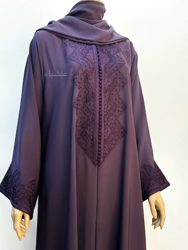 Front close-up view of A deep purple abaya made from Nida fabric featuring intricate geometric Magrabi hand embroidery along the front and sleeves, paired with a matching soft chiffon Sheila.