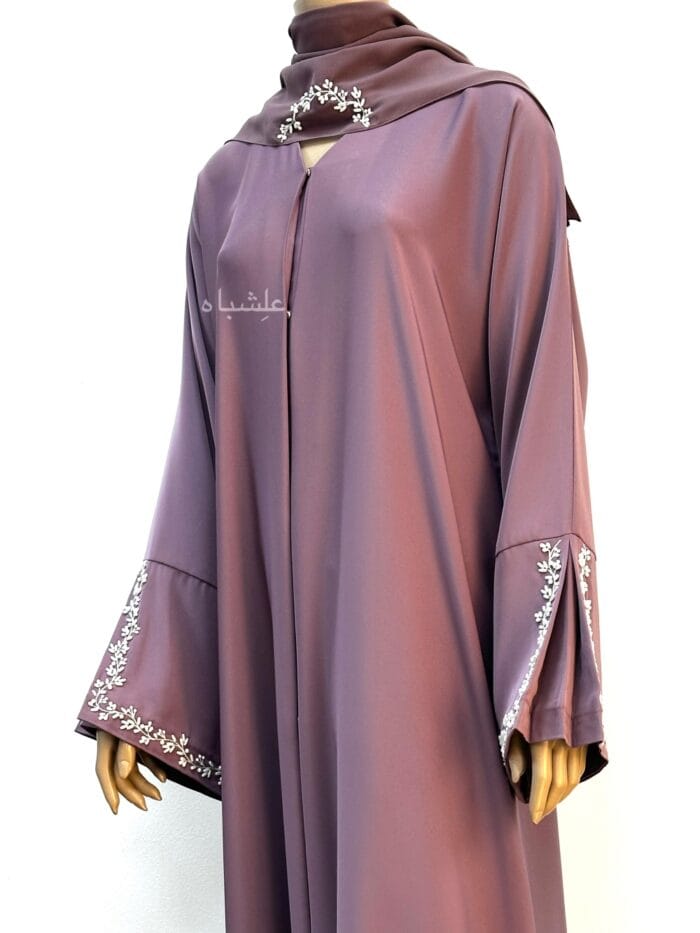 A mauve Nida Premium abaya with floral handwork on the sleeves and Sheila, featuring a folded sleeve pattern for a refined, elegant look.