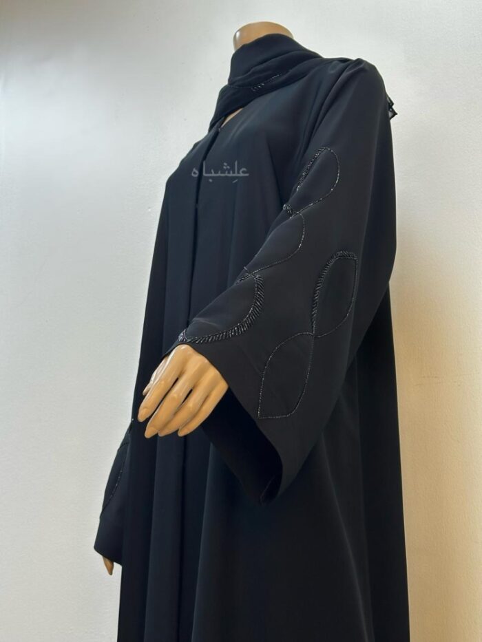 Flowing Loop Abaya viewed from a low angle, showcasing hands slightly raised, emphasizing the flowing design and intricate hand-stitched details.