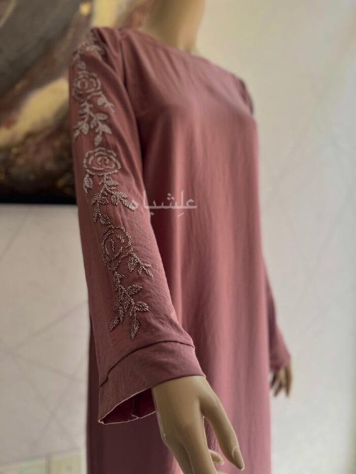 Close up front view of abaya with hands raised high showing the handwork on sleeves