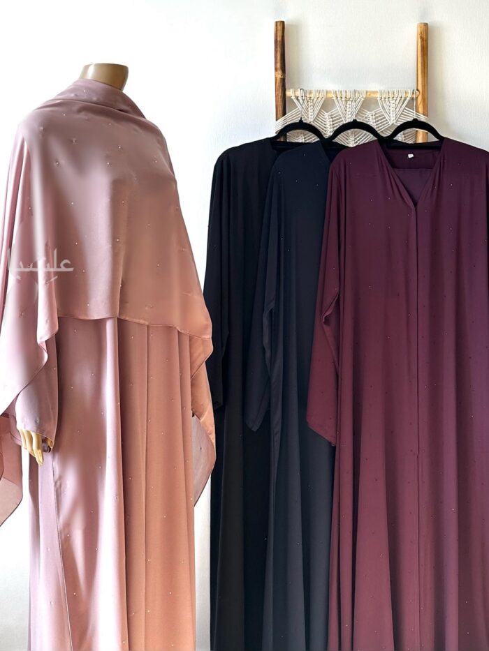 Photo of one rhine stone abaya on mannequin with 3 placed on ladder