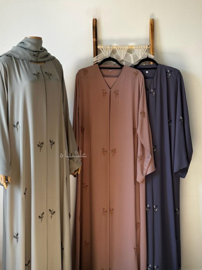 Front view of three abaya 2 on ladder and 1 on mannequin