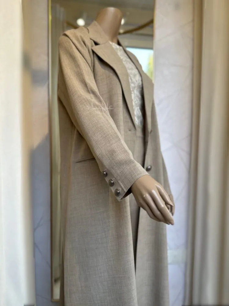 Side view with hand slightly lifted of a Mannequin wearing a cream linen abaya by Alishbah, featuring elegant button details on the front and sleeves, paired with a soft chiffon Sheila."