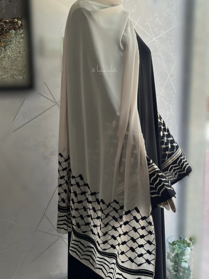 Abaya crafted from premium Nida fabric featuring intricate Keffiyeh embroidery on the sleeves and a soft chiffon Sheila. The Alishbah Keffiyeh Design Abaya blends contemporary elegance with cultural heritage, offering a sophisticated and graceful look.