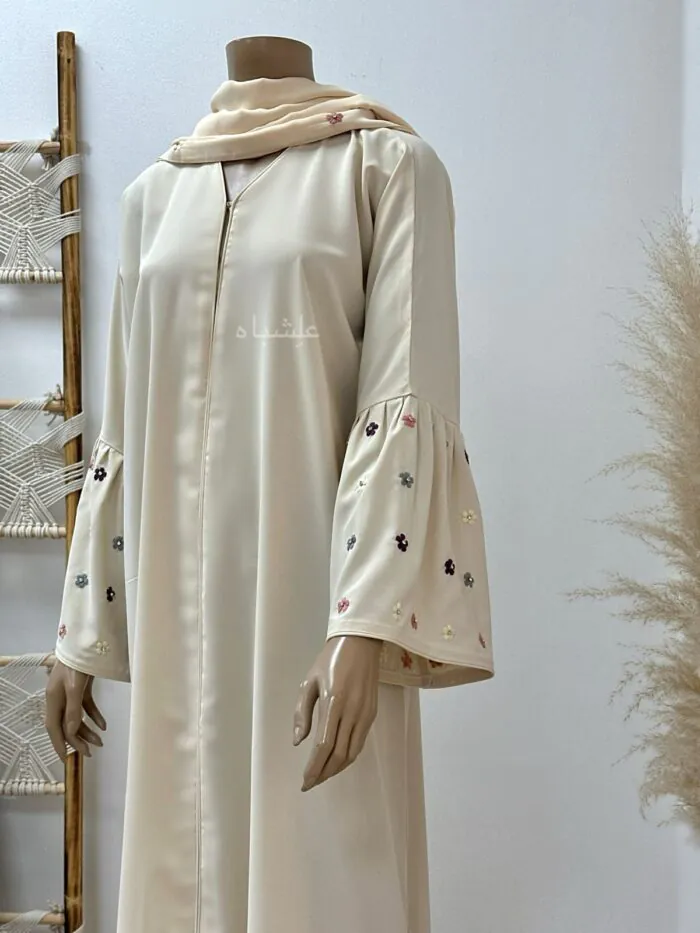 Close-up of Floral Bliss Cream Abaya from Alishbah, featuring delicate floral embroidery on Noor fabric