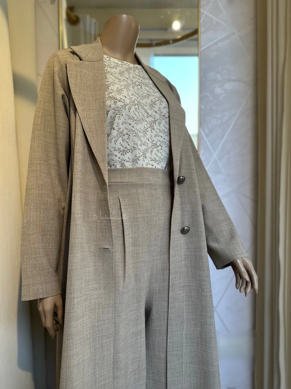 Front view with coat open showing inner dress with hands slightly up of a Mannequin wearing a cream linen abaya by Alishbah, featuring elegant button details on the front and sleeves, paired with a soft chiffon Sheila."