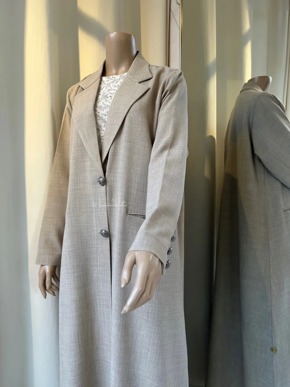 "Close-up of a Mannequin wearing a Cream linen abaya by Alishbah, featuring elegant button details on the front and sleeves, paired with a soft chiffon Sheila."