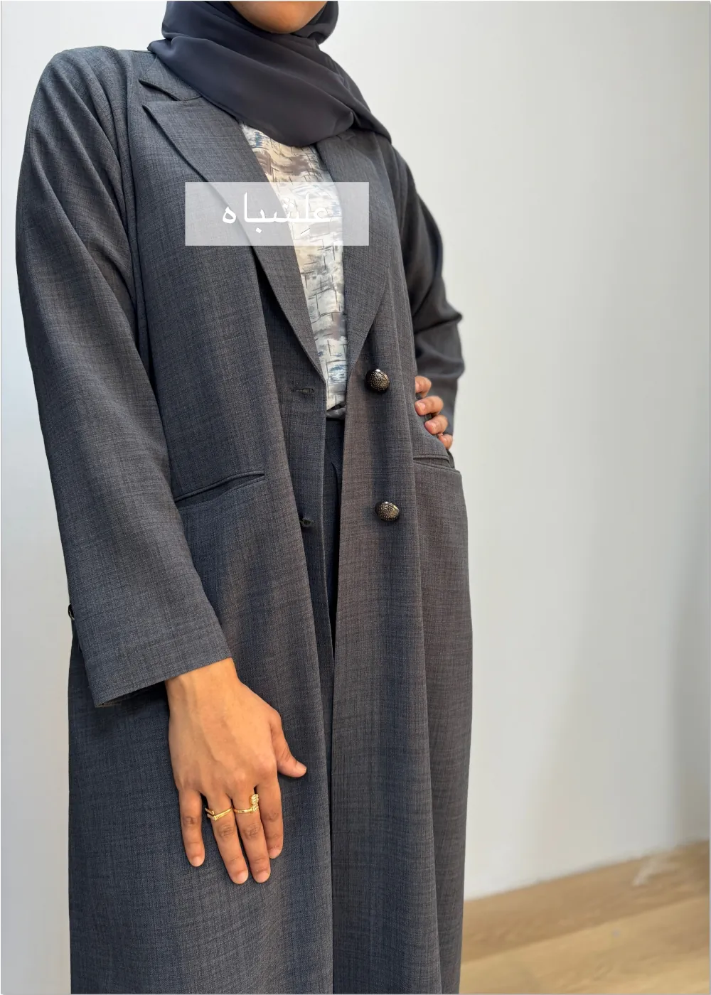 "Close-up of a woman wearing a black linen abaya by Alishbah, featuring elegant button details on the front and sleeves, paired with a soft chiffon Sheila."