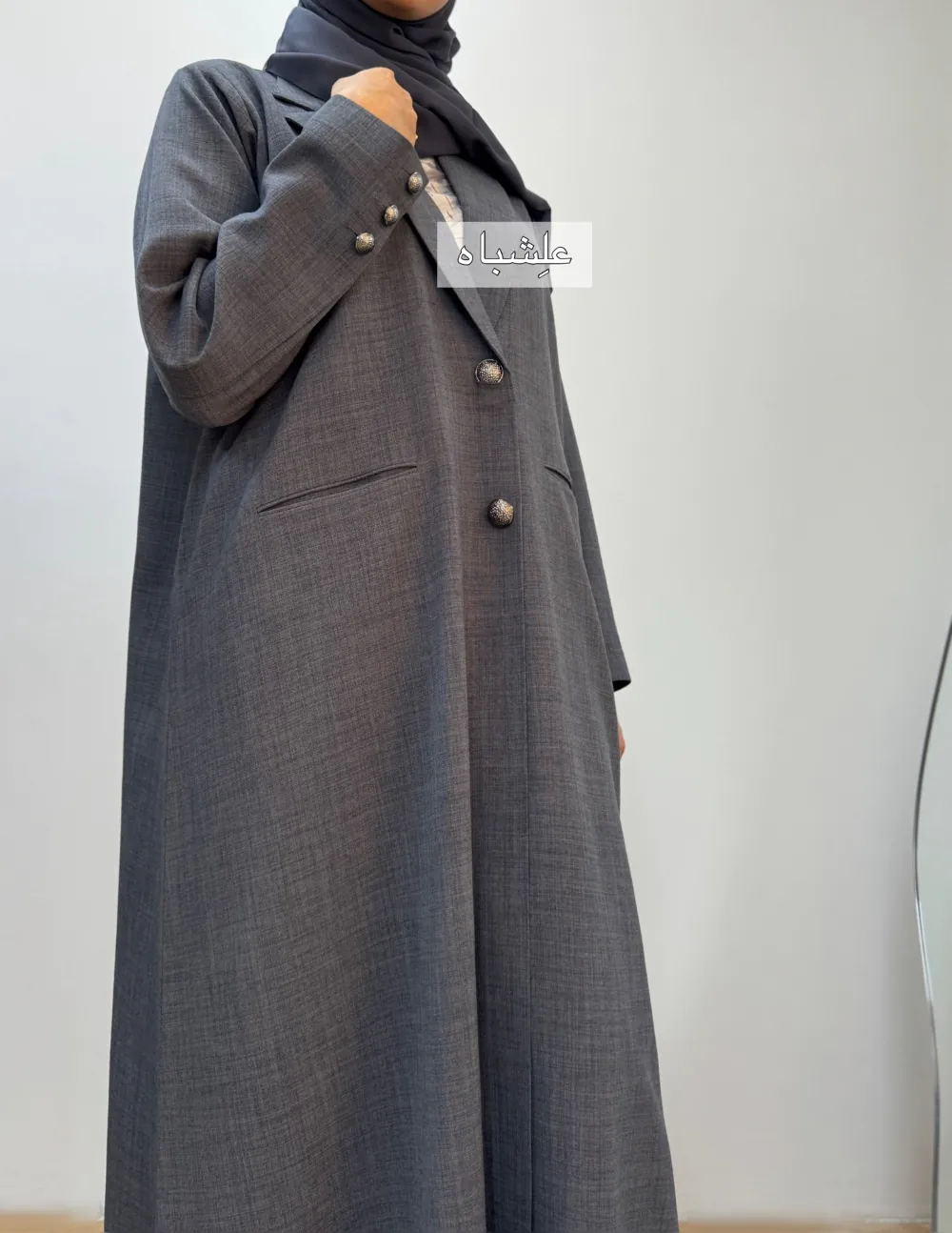 "Close-up of a woman wearing a black linen abaya by Alishbah, featuring elegant button details on the front and sleeves, paired with a soft chiffon Sheila."