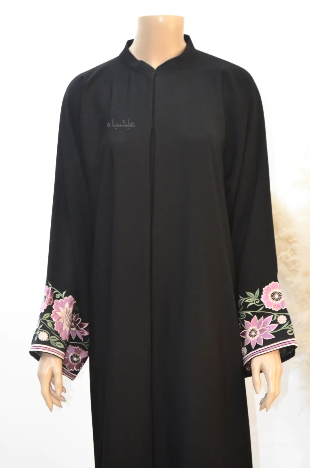 “Close-up image of the Floral Elegance Abaya, highlighting the intricate floral embroidery in pink, purple, and white along the sleeves. The black Nida Premium fabric is shown in detail, emphasizing the fine craftsmanship and elegant design of the abaya’s floral patterns.”