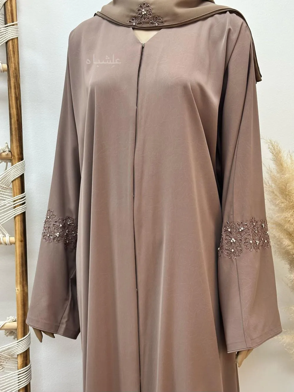 "Abaya from Alishbah crafted from Marble Crush fabric with a smooth, wrinkled texture. Features floral handwork and subtle bead accents on the sleeves and matching chiffon Sheila (28” width, 88” length)."