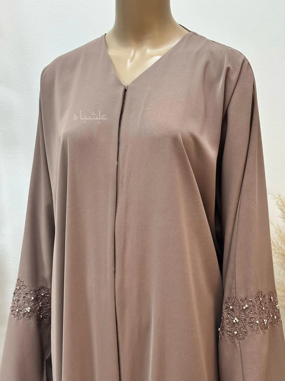 Front view of Abaya from Alishbah crafted from Marble Crush fabric with a smooth, wrinkled texture. Features floral handwork and subtle bead accents on the sleeves