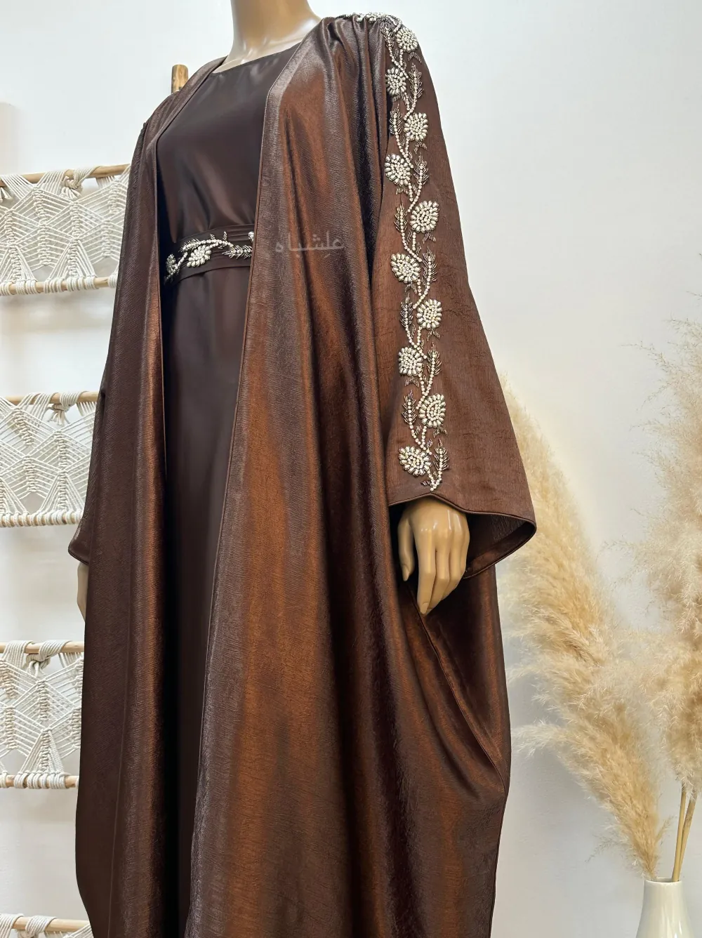 bronze abaya with delicate handwork on the sleeves and belt, featuring an inner layer and a belt that enhances the silhouette with a graceful flow.