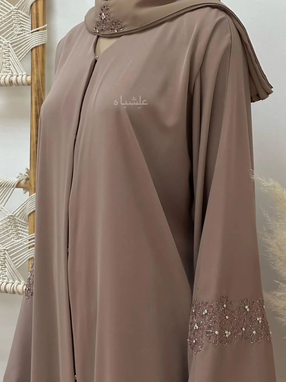 Side view of "Abaya from Alishbah crafted from Marble Crush fabric with a smooth, wrinkled texture. Features floral handwork and subtle bead accents on the sleeves and matching chiffon Sheila (28” width, 88” length)."