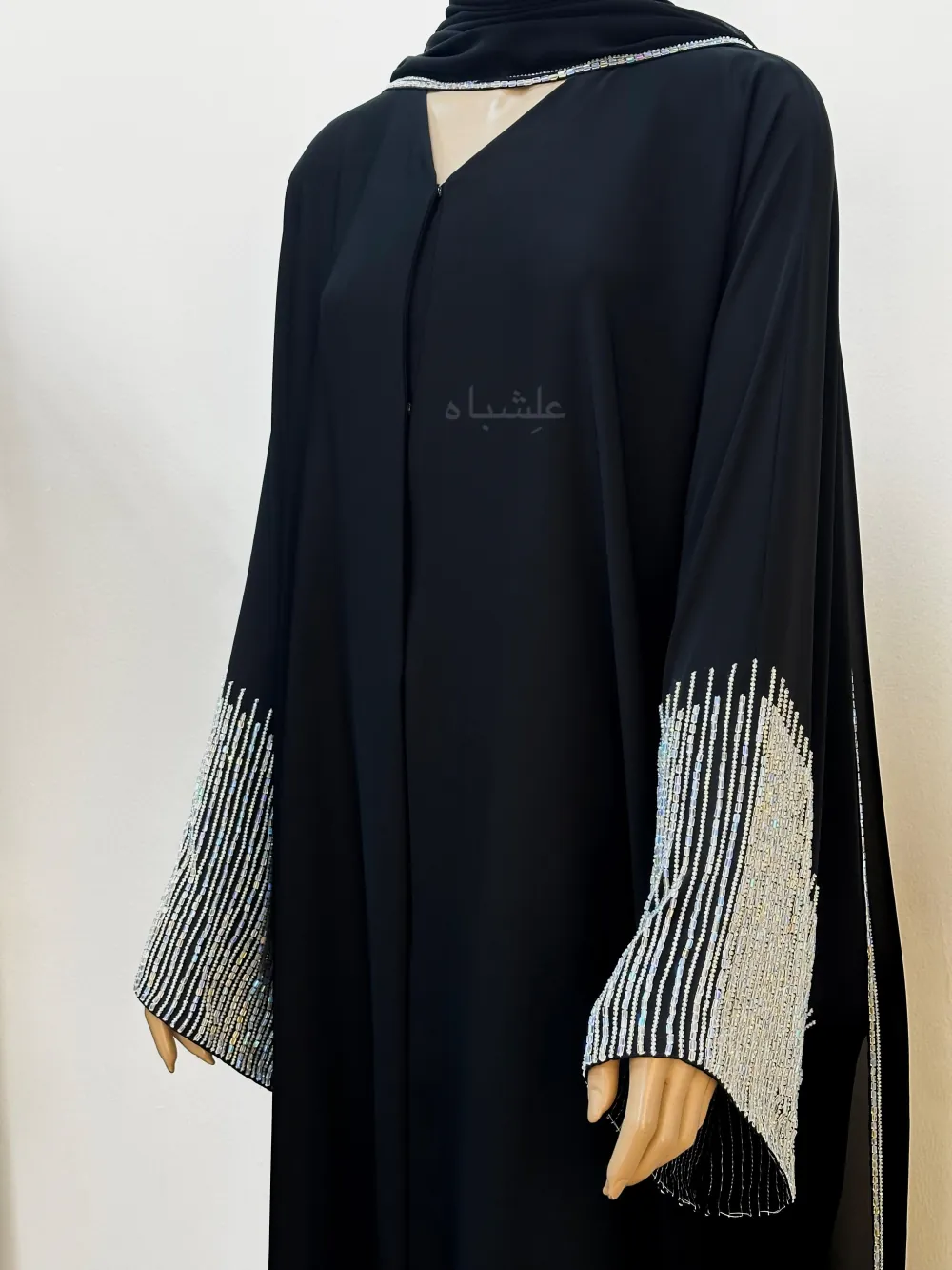 "close up view of the Crystal Noir Abaya, featuring flowing Nida fabric and delicate crystal stone detailing on the sleeves and along the side of the matching chiffon sheila, offering a blend of elegance and sophistication."