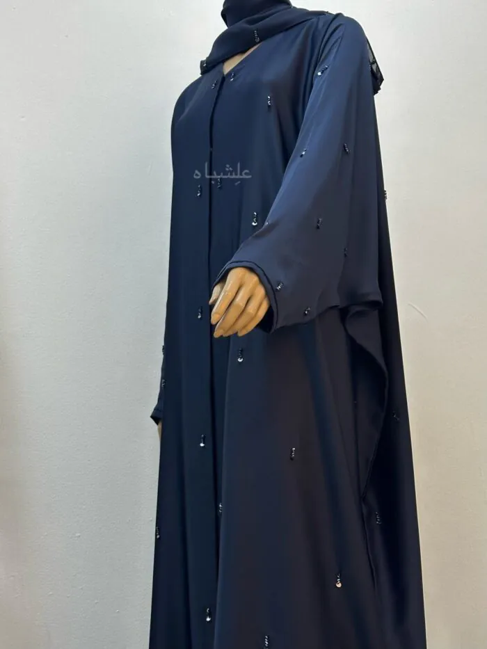 Side view with hands slightly raised of Midnight Dew Abaya by Alishbah, made from soft Maha fabric with handwork featuring cut stones and sequins, paired with a chiffon Sheila for a sleek and stylish look.