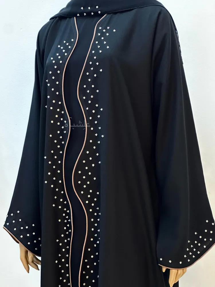 "Close-up front view of Wavy Grace Alishbah Abaya on a mannequin without the Sheila, highlighting the wavy-cut design and detailed hand-stitched accents along the front."